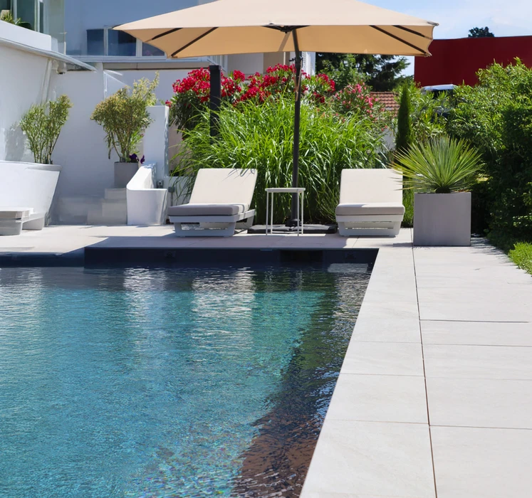 Espace extérieur avec piscine moderne aux eaux turquoise, terrasse en dalles de pierre naturelle beige