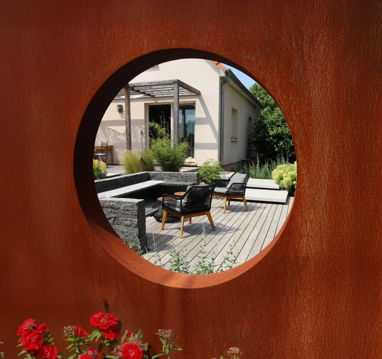Terrasse extérieure moderne avec salon de jardin en rotin noir et coussins blancs sur plancher bois