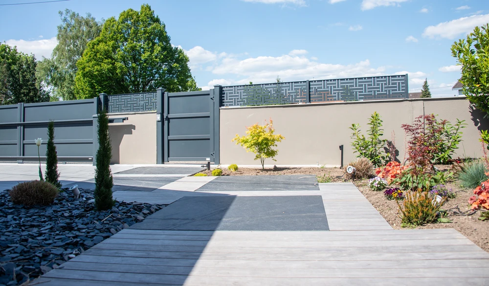 Aménagement paysager moderne d'entrée résidentielle avec portail coulissant gris anthracite à motifs géométriques ajourés