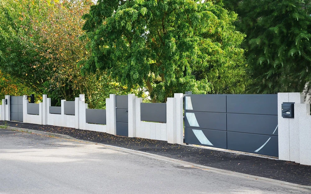 Clôture résidentielle moderne en béton et métal installée le long d'une voie publique