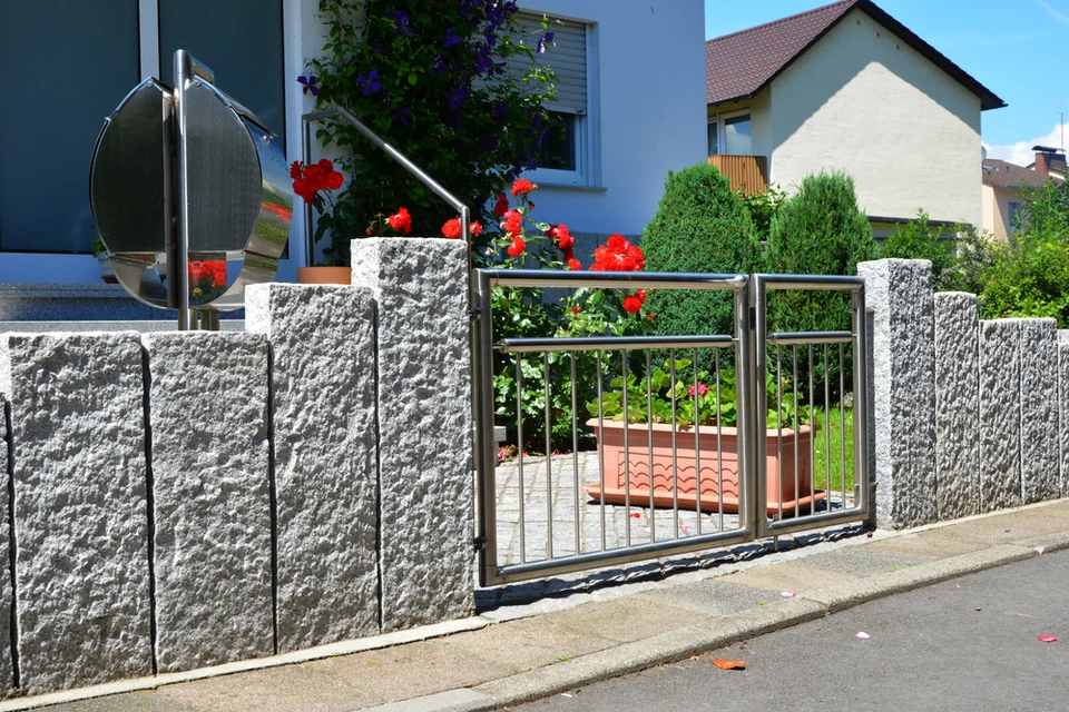 Extérieur résidentiel avec portail automatique en inox et clôture en blocs béton texturé gris