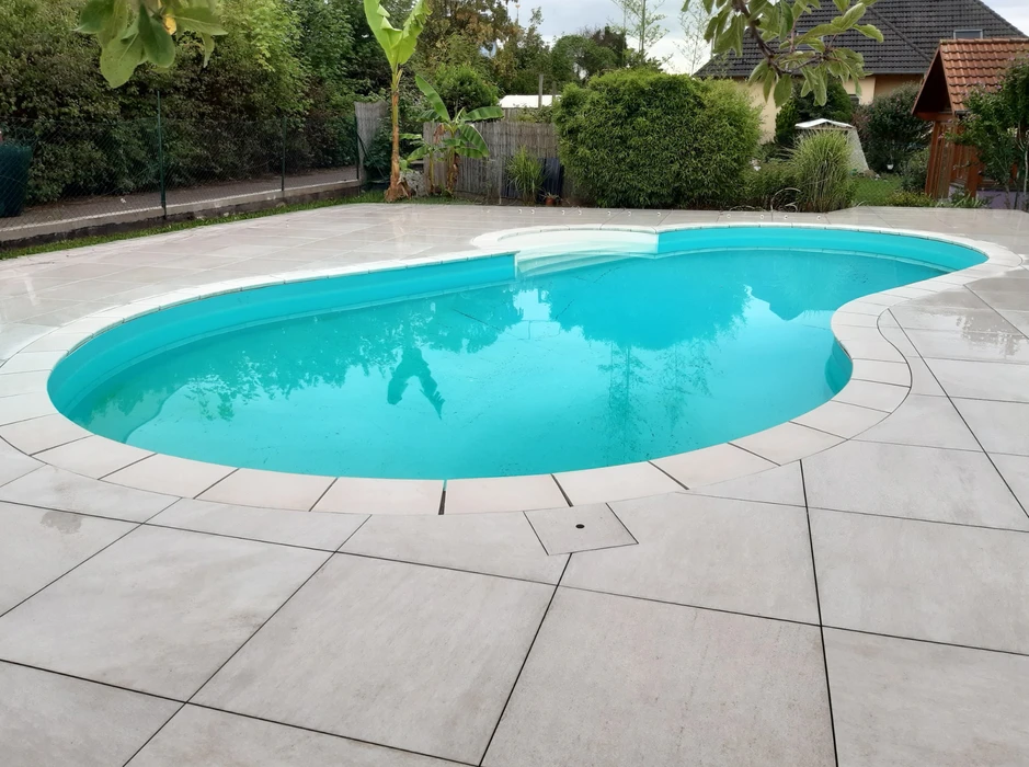 Piscine extérieure résidentielle de forme libre avec spa intégré, située dans jardin paysagé