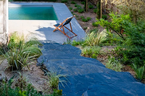 Aménagement paysager extérieur avec piscine contemporaine, chaise longue en bois et toile noire