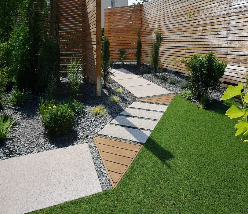 Jardin résidentiel avec terrasse en bois, pelouse entretenue, massifs paysagers et arbres d'ornement