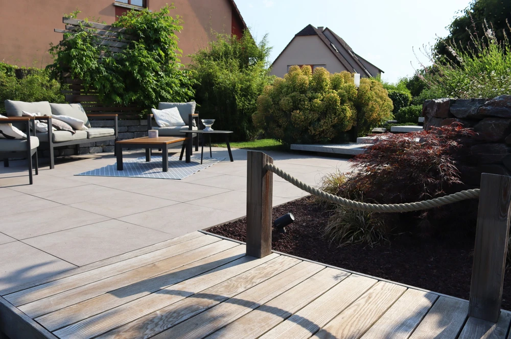 Terrasse extérieure avec piscine rectangulaire aux eaux turquoise, entourée de dalles en béton gris clair disposées en motif régulier