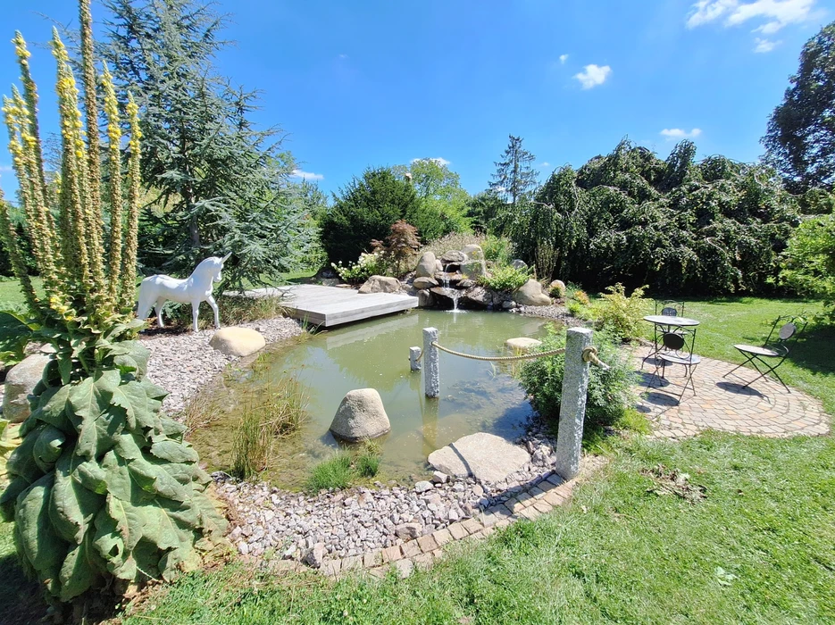 Aménagement paysager résidentiel moderne avec escalier extérieur en bois, muret de soutènement courbe et plantation diversifiée
