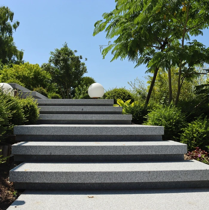 Scène extérieure d'aménagement paysager en terrasses avec escalier en pierre naturelle, murets de soutènement, plantation de cyprès, lavandes et arbustes méditerranéens