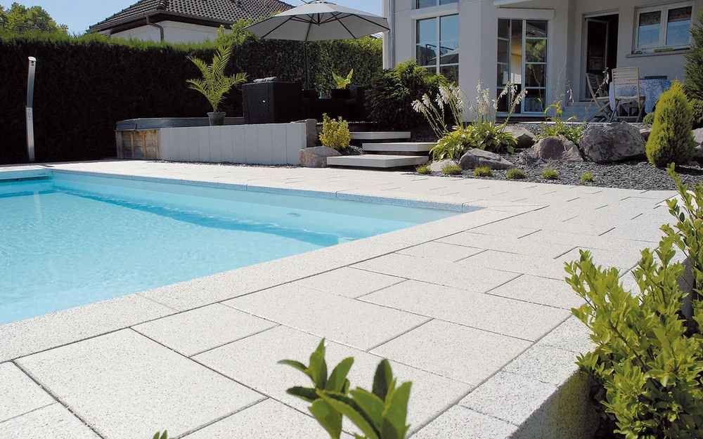 Espace extérieur contemporain avec piscine rectangulaire à débordement, terrasse en dalles de pierre naturelle claire