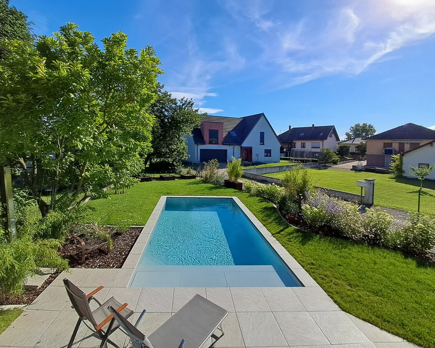 Espace extérieur contemporain avec piscine rectangulaire à débordement, terrasse en dalles de pierre naturelle claire