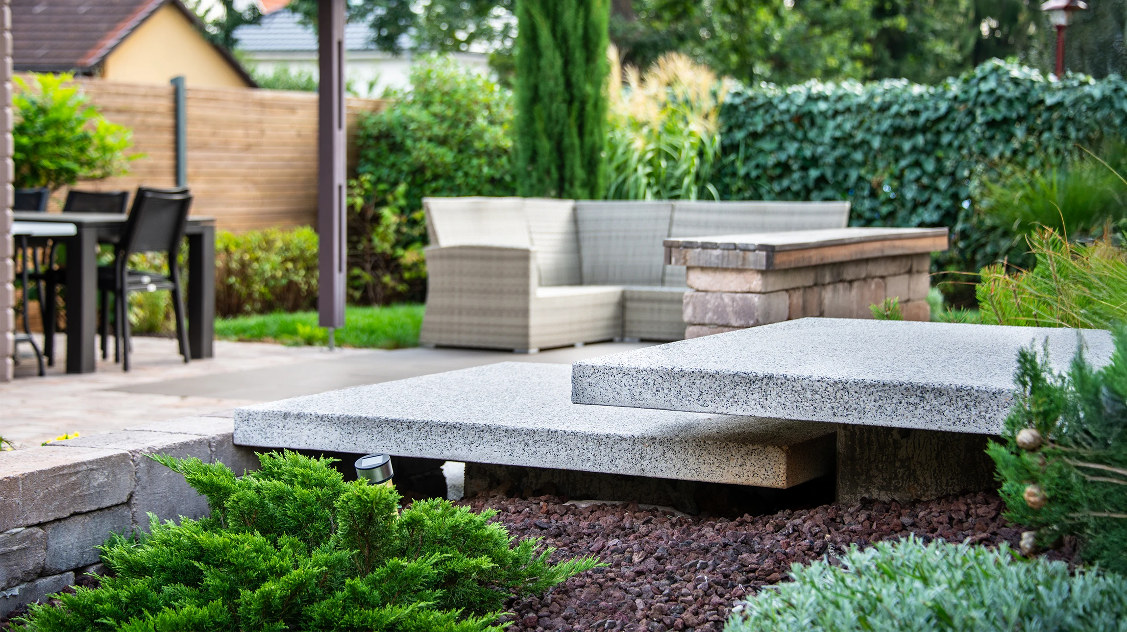 Jardin extérieur avec muret en pierres sèches de différentes tailles et couleurs, certaines couvertes de mousse